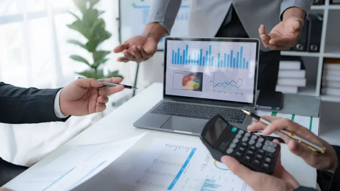 Discussione di analisi dati aziendali con grafici su laptop e documenti.