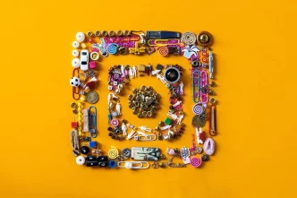 Logo di Instagram creato con vari piccoli oggetti su sfondo giallo.